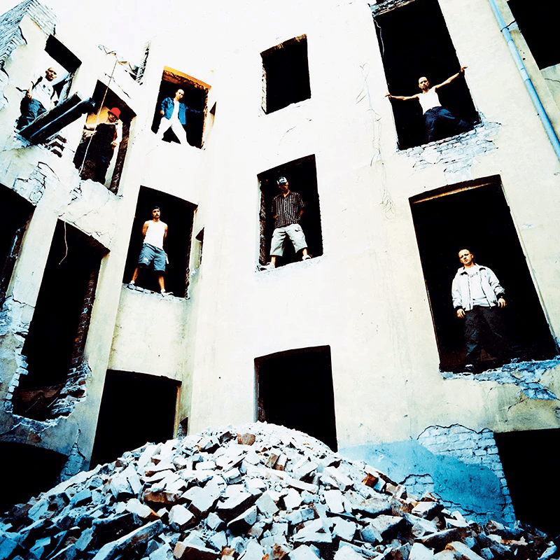 Gutta står i dørar i en blokk som er i ferd med å rives.